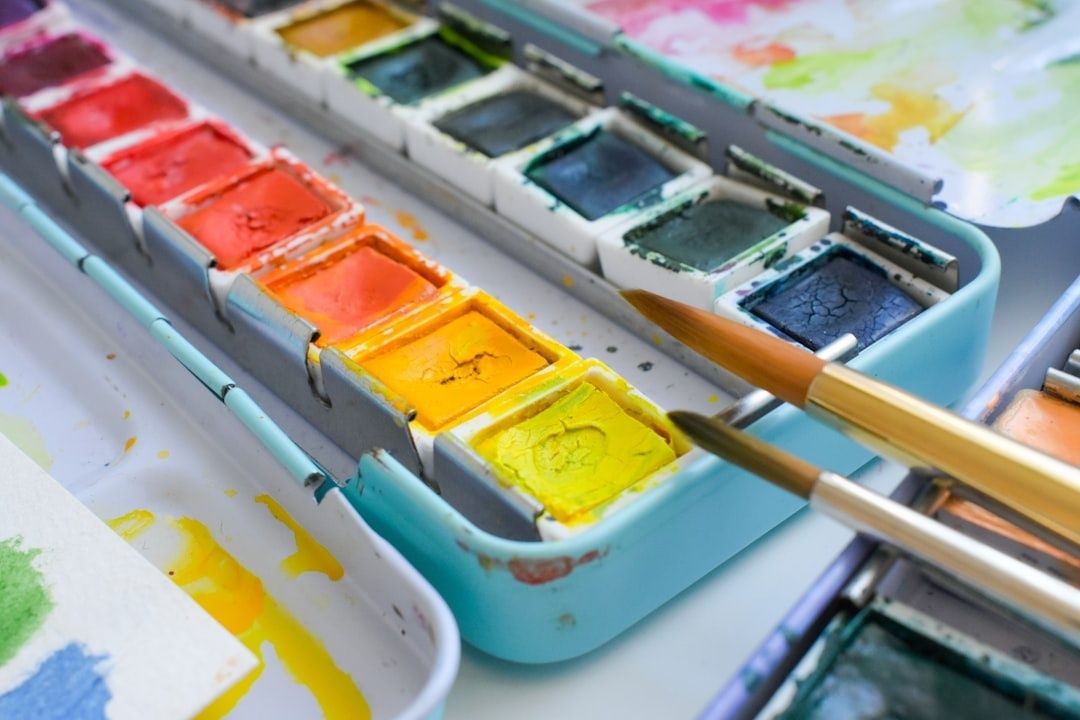 Open watercolor palette with vivid pigments and brushes