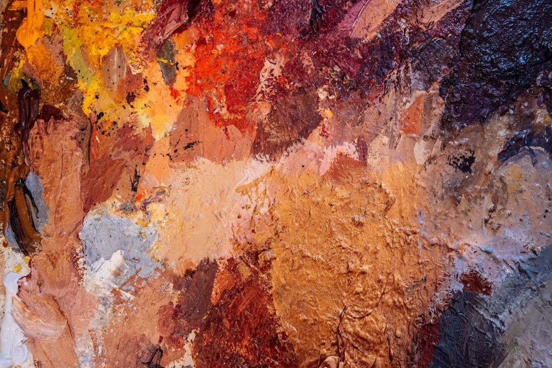 Close-up of thick, multicolored oil paint layered across a palette