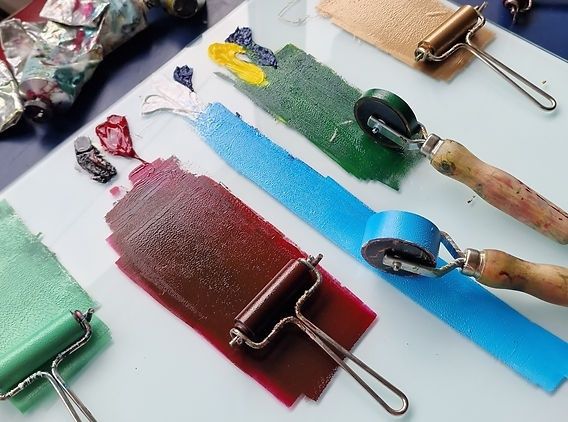 Brayers spreading colorful ink across strips of paper